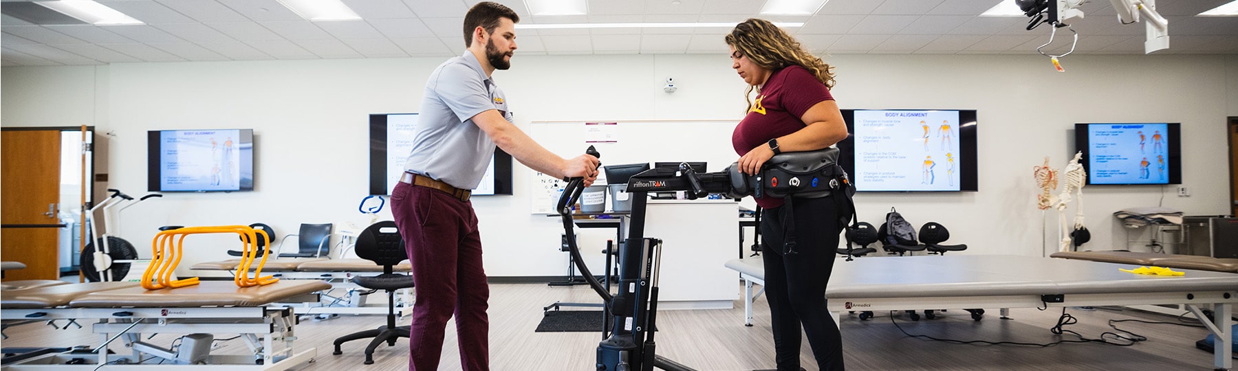Two Physical Therapy students exam practicing gait exercises in the Physical Therapy lab.
