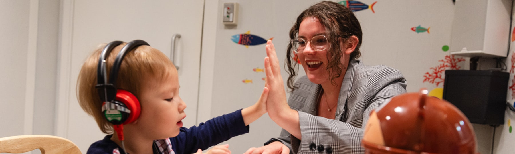 Speech Language Pathology student and toddler giving each other a high five.