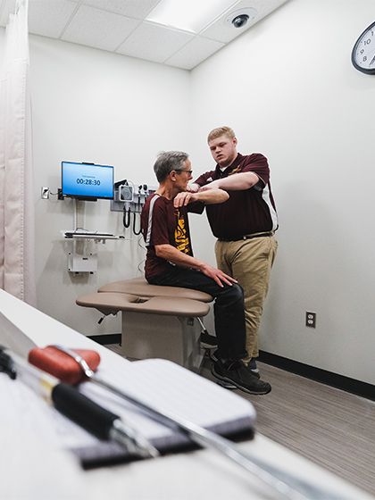 Athletic training student adjusting a patient's shoulder