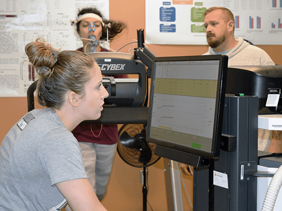 Student on treadmill being monitored by athletic trainer