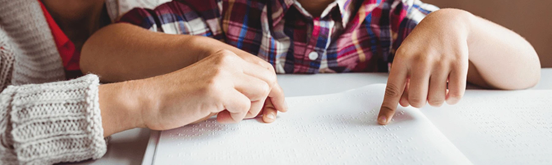 Deaf blind intervener helping a person use braille