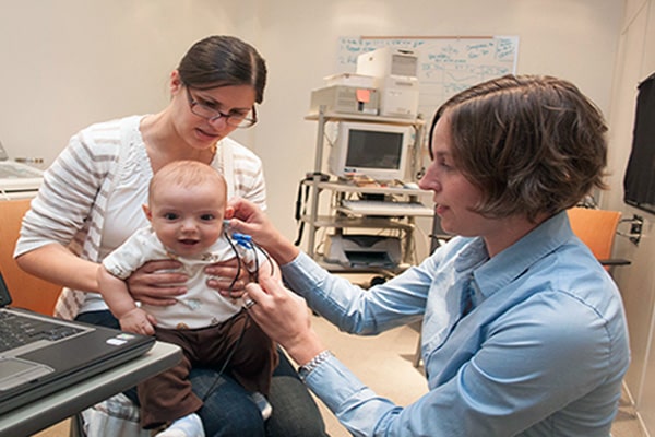 Faculty member performing an infant hearing screening.