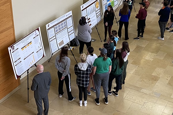Students, faculty, and staff viewing posters at the College of Health Professions Research Symposium.