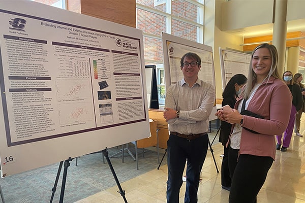 Two students pose in front of a research poster in the College of Health Professions.