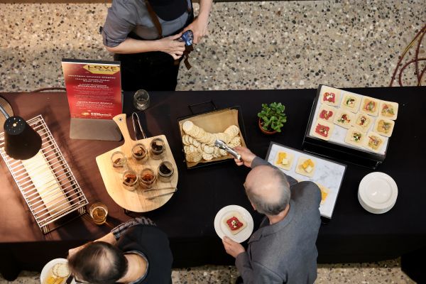 Overhead view of people selecting food from catered refreshment table at an indoor event.
