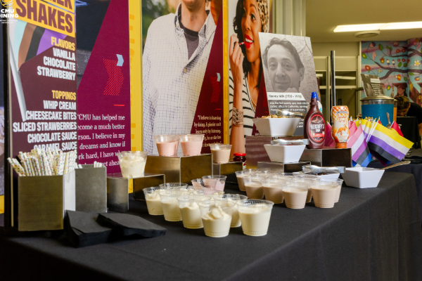 Dessert and milkshake samples displayed on a catering table with promotional signage at an event.