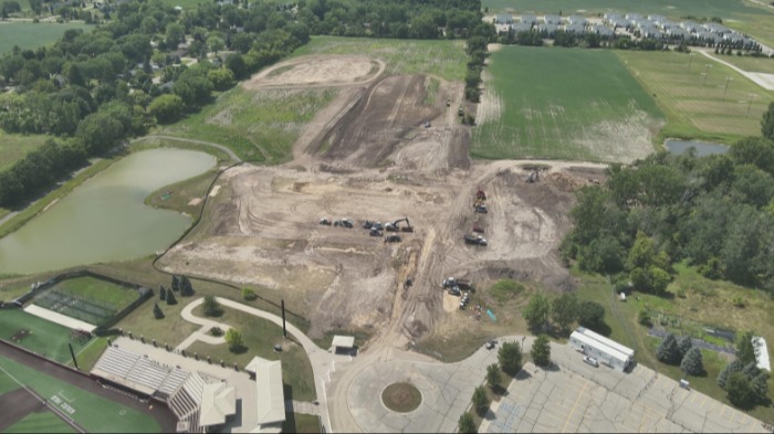 Golf practice facility construction site west of baseball stadium with a lot of land earthwork underway and buildings in the background