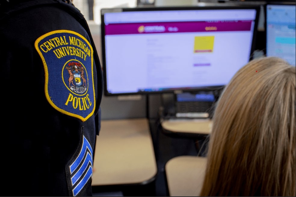 Police Badge Dispatcher and Sergeant speaking about a case in the dispatcher center in low light with computers.