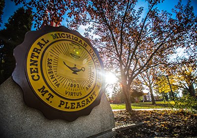 Sun flares behind Central Michigan University seal