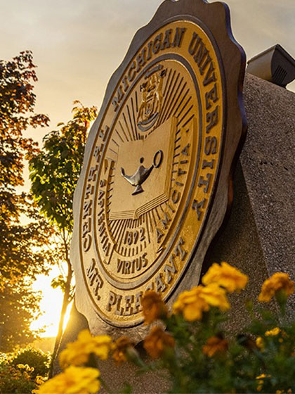 CMU seal on campus in a sunrise setting