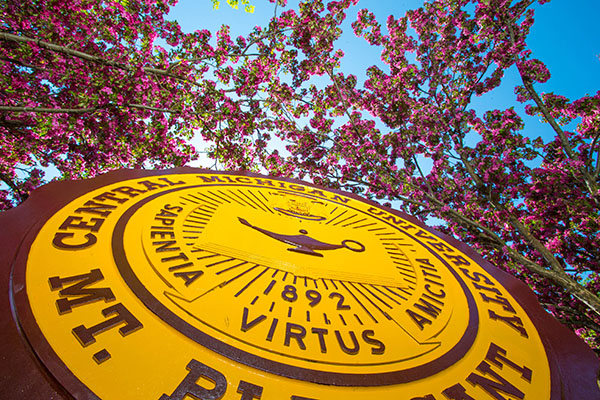 Central Michigan University Seal with trees and blue sky in background