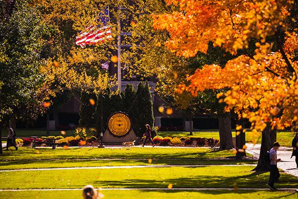 CMU seal and USA flag on campus with fall colors