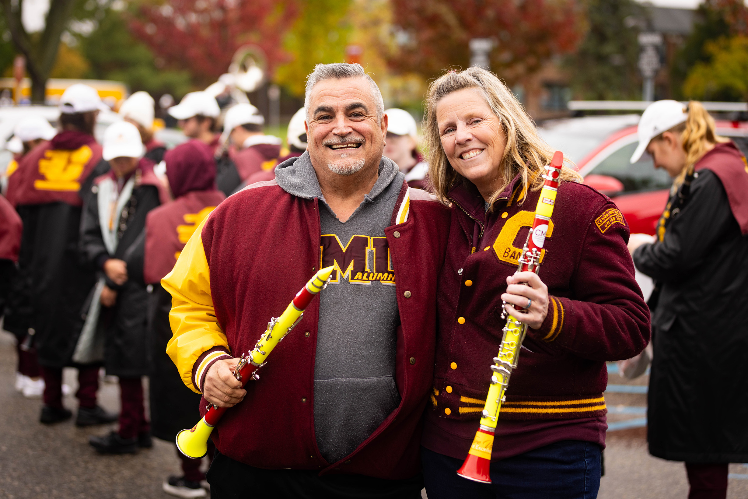 CMU Marching Band Alumni smiling with their instruments during the 2023 Homecoming parade.