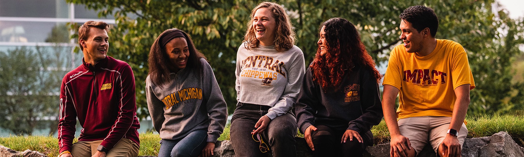 Students sitting in front of library_1800x540 Students smiling and sitting in front of the library.