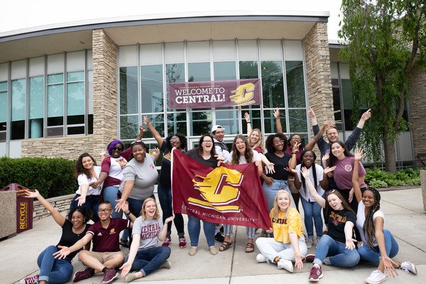 Students smiling and cheering as they welcome others to orientation.