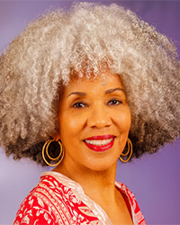 A smiling woman in a portrait against a purple background.