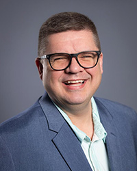 Ryan Fewins-Bliss wearing glasses and a blue suit