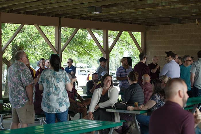 OIT staff seated at picnic tables and walking around a wooden park pavilion.