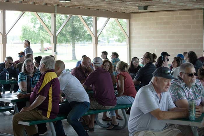 OIT staff seated at picnic tables and walking around a wooden park pavilion.