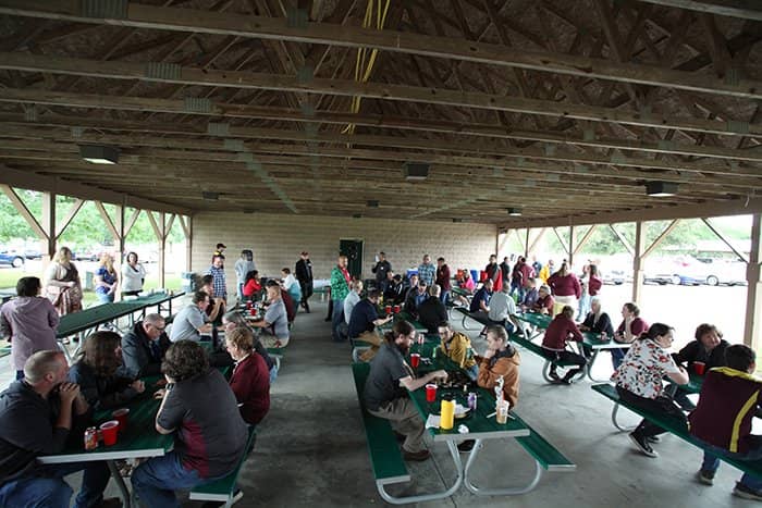 OIT staff seated at picnic tables and walking around a wooden park pavilion.