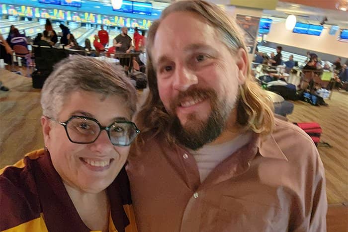 Kelly and Ben pose for a photo at Riverwood. Kelly is wearing a maroon and gold CMU polo shirt and Ben a tan dress shirt.
