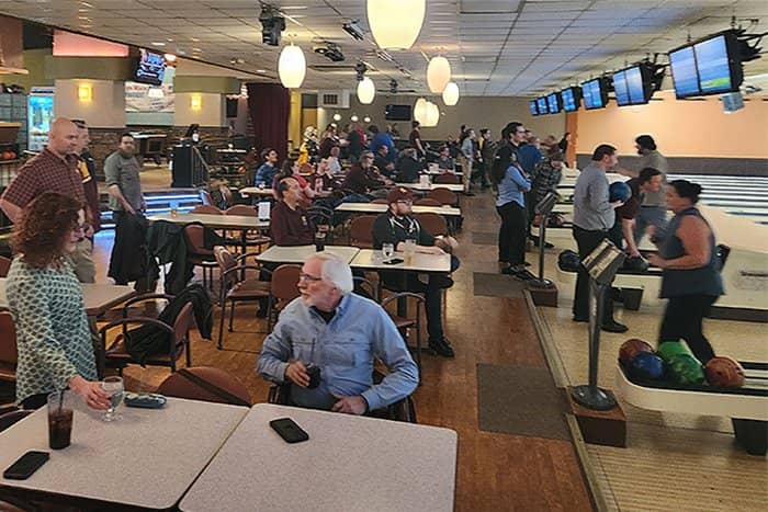Wide angle photo of OIT staff talking and bowling at Riverwood.