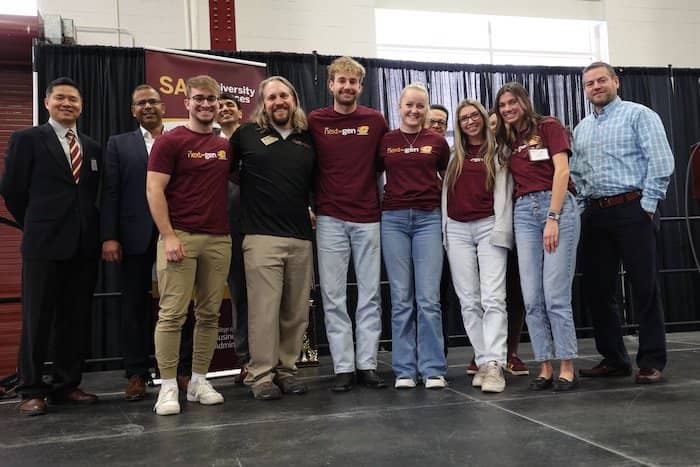 Photo of faculty, students, and guests standing shoulder to shoulder on the stage.