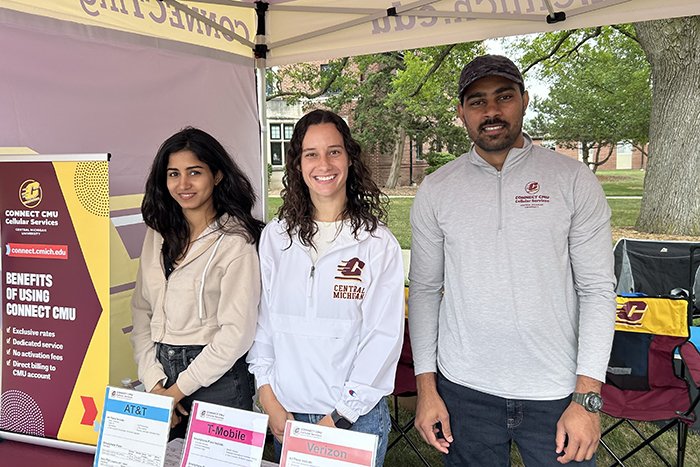 Three staff members pose for a photo under the tent.