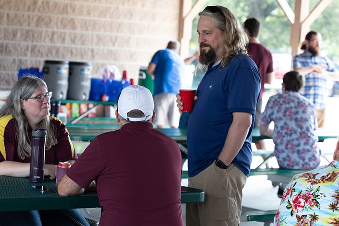 Three colleagues talking at a picnic table.
