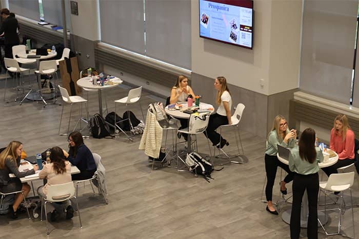 Students seated at tables in the atrium of Grawn Hall.