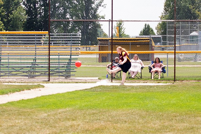 The kicker makes contact and heads toward first base while fans look on.