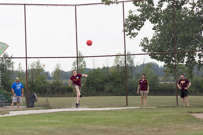 A kicker launches a ball high into the air from home plate.