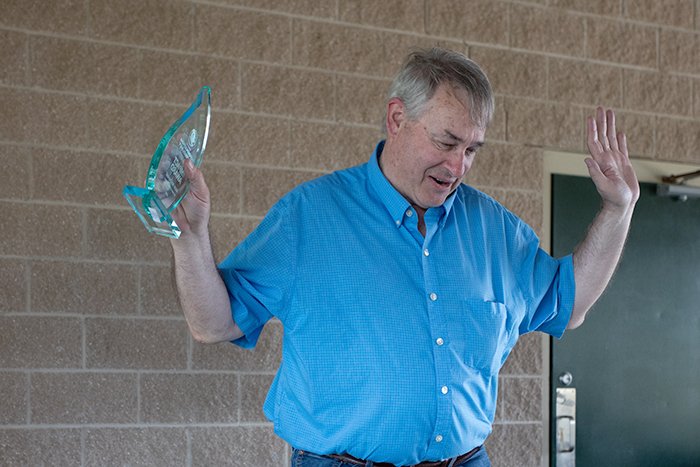 Mark raises his hands in an attempt to get the crowd to stop clapping for him as he returns to his seat.