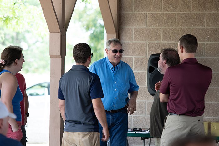 A group of coworkers talk in under the pavilion.