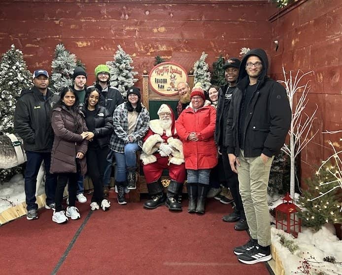 A group of students and their supervisor pose for a photo with Santa a local reindeer farm.