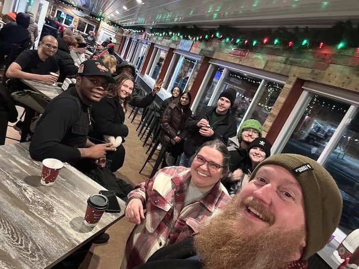 A group of students and their supervisor smile for the camera while on an evening gathering a local reindeer farm.