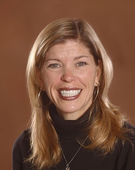Professional headshot Dr. Anne Hornak in dark attire against a brown background.