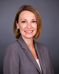 Professional headshot of Jennifer Cotter, Interim Vice President for Advancement, in a grey suit in front of a grey background
