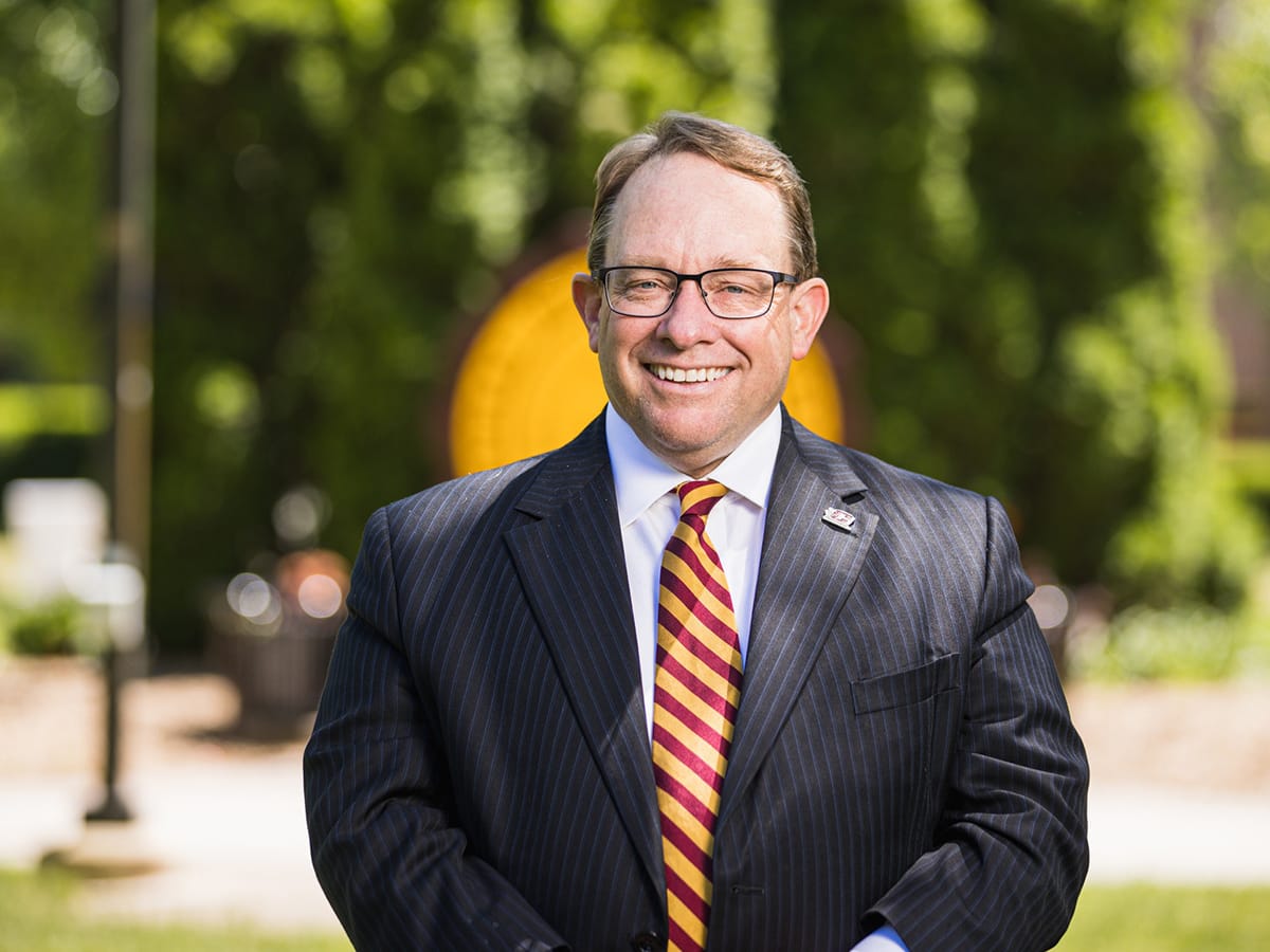 President Emeritus Davies standing in front of seal