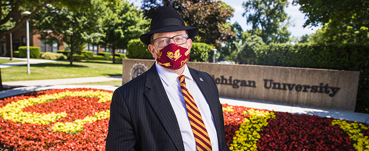 CMU President Bob Davies in front of CMU wall with logo and CMU flower bed
