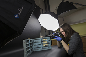 A woman taking a photo of a miniature model ships.