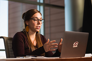 Young women interacting with online class on computer screen.