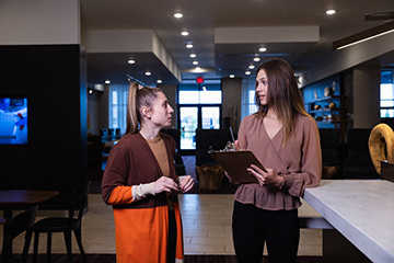 A woman talking to another woman inside a hotel lobby.