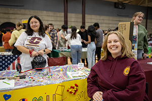 A student sitting in front of an RSO booth with another student