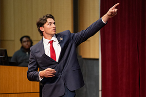 A man in a suit and red tie pointing his finger.