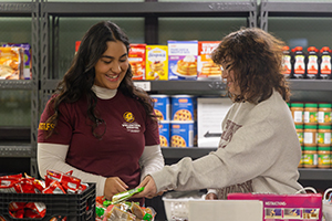 Two students discuss over a pile of perishable foods in the student food pantry