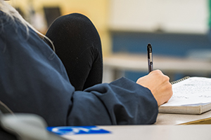 Zoomed in shot of a student holding a pen and writing in her notebook
