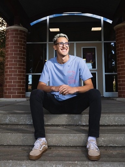 Walter Centeno sits outside a residence hall and smiles