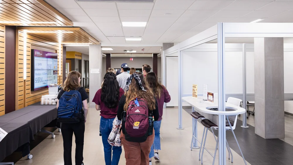 A group of students walking in a hallway inside the College of Business Administration at Central Michigan University.