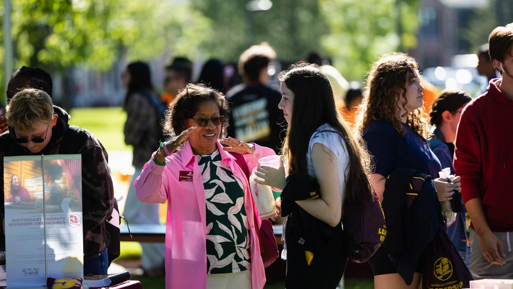 Students, faculty and staff standing outside on Central Michigan Universities campus as they talk at a CMU event/job fair.